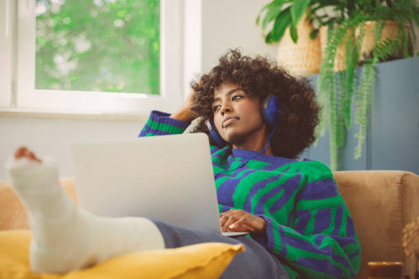 istock Sad young woman with broken leg resting at home 1661021014