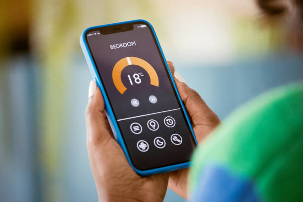 istock Woman using mobile phone to control termostat at home 1661021671