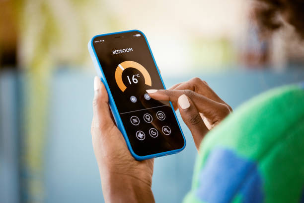 istock Woman using mobile phone to control termostat at home 1661021704