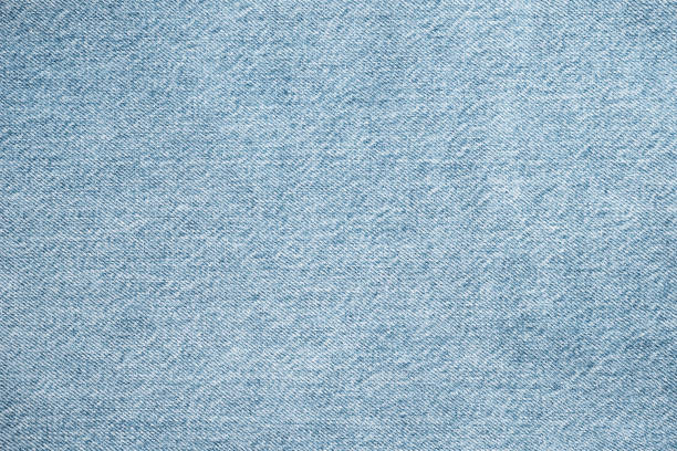 Texture of light blue jeans close up. Dark denim background.