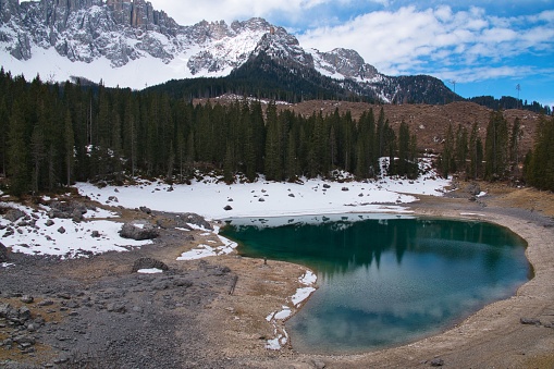 A scenic serene landscape of the Karersee in South Tyrol surrounded by snow-covered peaks