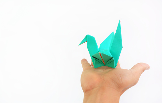 Origami bird flying on people hand on white background.