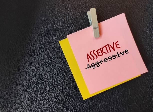 istock Pink note on black copy space background with text written AGGRESSIVE crossed off to ASSERTIVE, means to develop assertiveness or ability to express opinion positively with honest confidence to self and others 1661075538