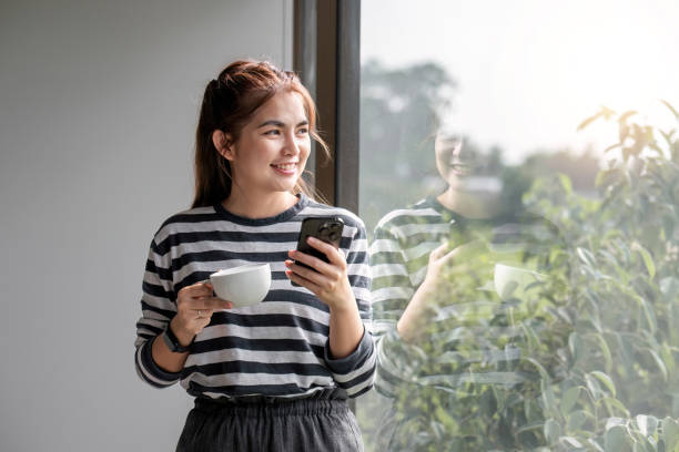 портрет красивой молодой женщины с чашкой кофе и в наушниках, стоящей расслабленной и счастливой. - room service audio стоковые фото и изображения