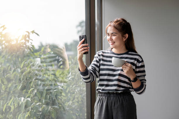 retrato de bela jovem mulher com uma xícara de café e usando fones de ouvido em pé relaxado e feliz. - room service audio - fotografias e filmes do acervo