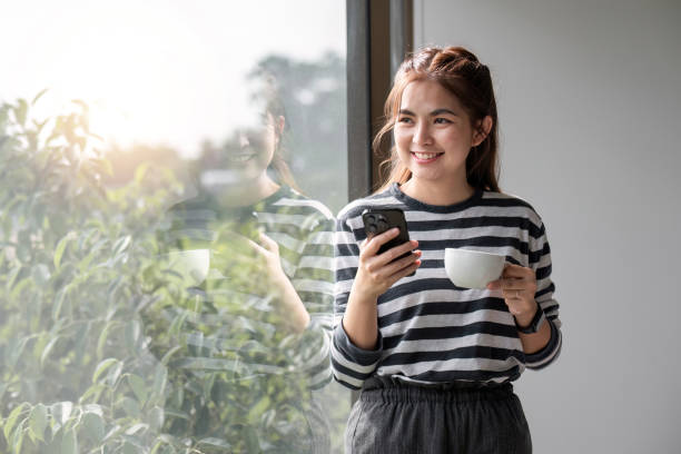 retrato de bela jovem mulher com uma xícara de café e usando fones de ouvido em pé relaxado e feliz. - room service audio - fotografias e filmes do acervo