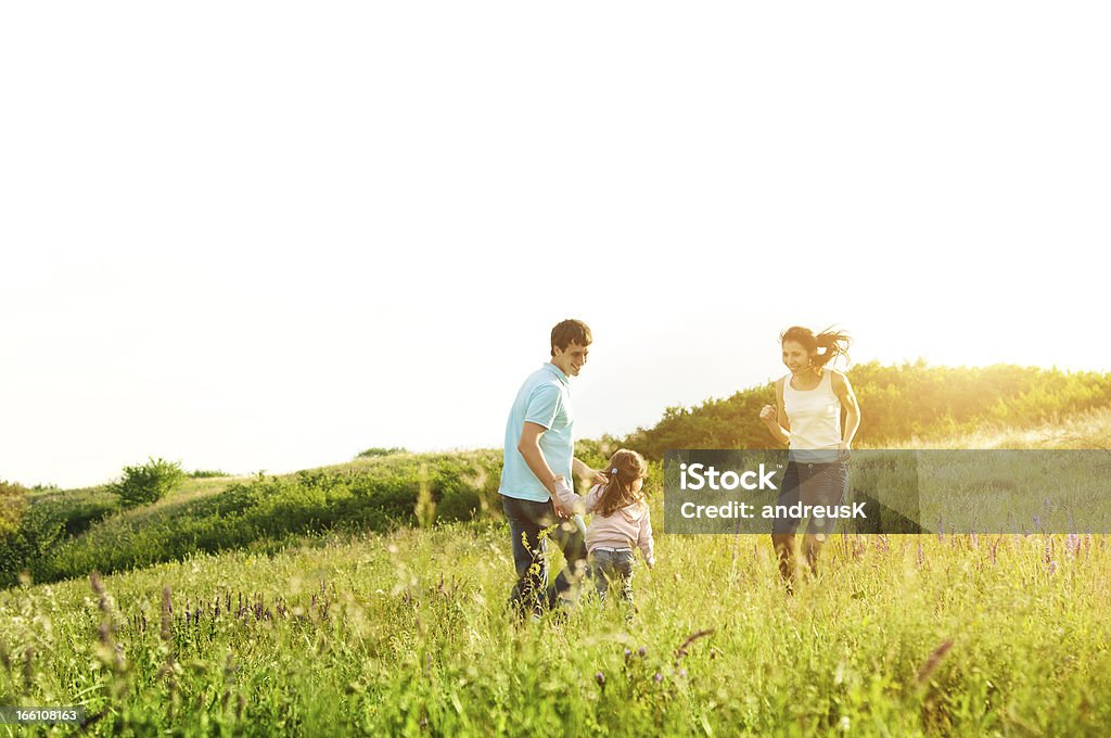 Young family in meadow with lens flare happy family having fun outdoors Adult Stock Photo