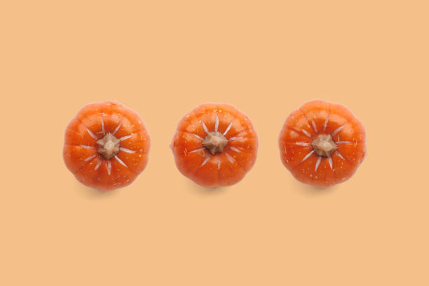 istock Three orange pumpkins on pastel color background 1661085284