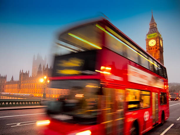 Big Ben with the Houses Of Parliament and a red double-decker bus passing at dusk