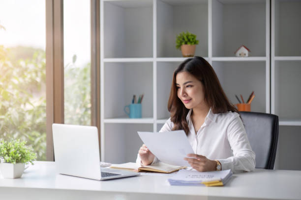 istock Young beautiful business woman using laptop and checking documents while working on laptop 1661089086
