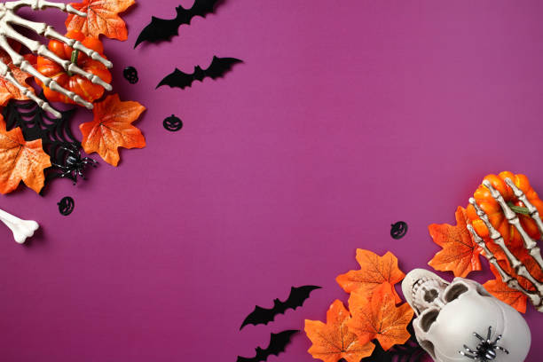 istock Happy Halloween flat lay composition. Top view pumpkins with skeleton hands, skull, fall maple leaves, bats on purple background. Halloween banner, party invitation card mockup. 1661104389