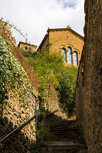 Saint-Mathieu d'Oingt church and its golden stone facade typical of this Beaujolais region from Rue du Bourg d'En Bas