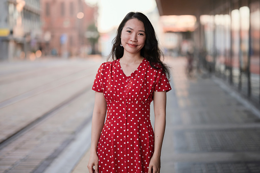 Model outdoors in the city wearing red dress. Image with copy space. South East Asian woman Vietnamese ethnicity