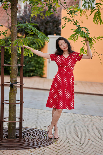 Model outdoors in the city reaching out for a branch. South East Asian woman Vietnamese ethnicity