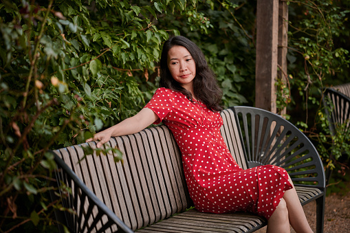 Model outdoors in the city wearing a red polka dot dress. South East Asian woman Vietnamese ethnicity