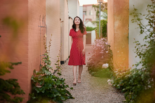 Model outdoors in the city wearing romantic red polka dot dress. South East Asian woman Vietnamese ethnicity