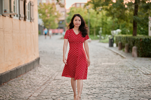 Asian model outdoors in the city walking in street looking at camera. Image with copy space. South East Asian woman Vietnamese ethnicity