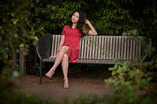 Model outdoors in the city wearing a red dress. South East Asian woman Vietnamese ethnicity