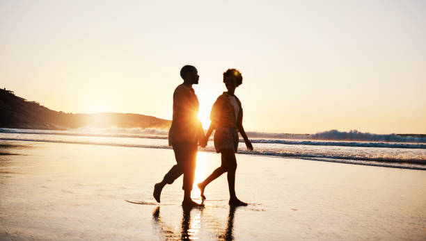 istock Beach sunset, silhouette and couple walking, holding hands and enjoy romantic conversation, freedom and travel holiday. Love, sea and dark shadow of people bonding, talking and relax on tropical date 1661137821