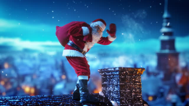 Cheerful Santa Claus Carrying a Red Bag with Gifts and Presents to Children, Walking on a Roof of a House on Christmas Eve. Santa Waving To Camera and Magically Disappearing into the Chimney