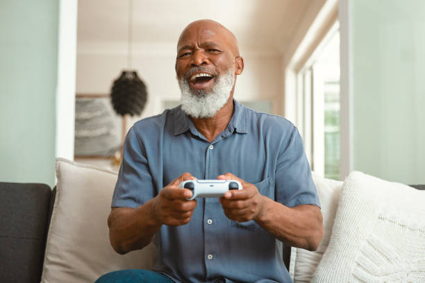 istock Senior Gamer: An Elderly Man Enjoying Video Games from His Sofa at Home 1661144937