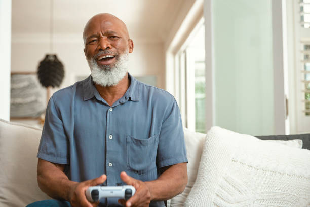 istock Senior Gamer: An Elderly Man Enjoying Video Games from His Sofa at Home 1661144942