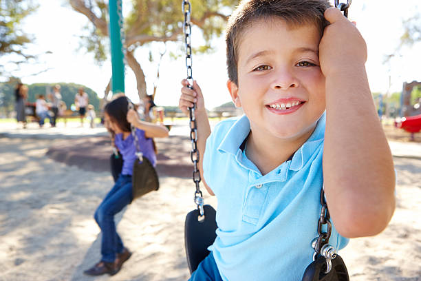 menino e uma menina brincando de balanço no parque - swinging sister family child - fotografias e filmes do acervo