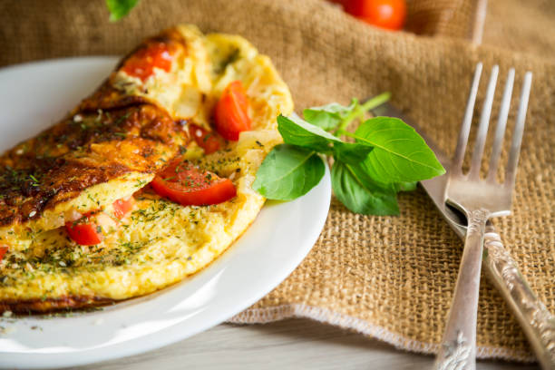 istock Stuffed omelette with tomatoes on a light wooden background. 1661149551