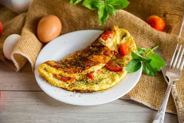 istock Stuffed omelette with tomatoes on a light wooden background. 1661150590