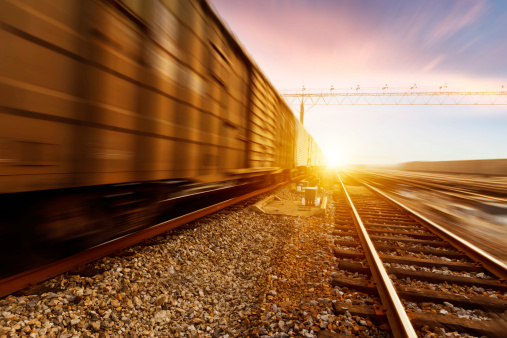 At sunset, fast moving freight train, drawing out of the station