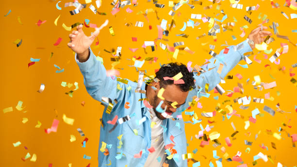 Foto de estúdio de homem com síndrome de Down comemorando grande vitória regado em confetes de tinsel - foto de acervo