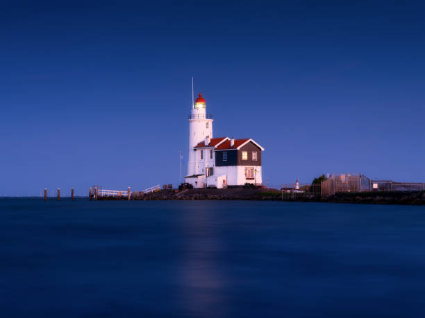 istock A lighthouse on the beach during blue hour. A landmark in maritime navigation. Long exposure. Natural composition. Photo for wallpaper and background. Paard van Marken, Netherlands. 1661157209