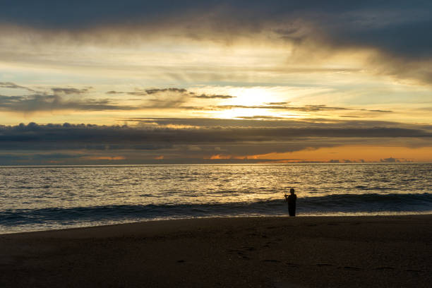 istock fisherman on beach against setting sun and cloudscape 1661157753
