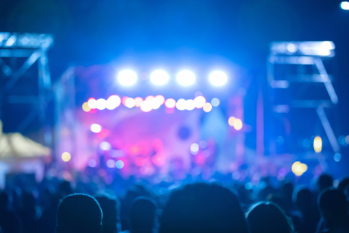 Silhouettes of concert crowd with stage lights, out of focus blurred photo