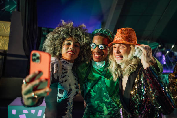 Haunted Howl-o-ween Bash A group of young friends wearing fancy dress costumes on a night out during halloween, standing in a nightclub in Newcastle, North East England. They are taking a selfie together on a mobile phone. weben stock pictures, royalty-free photos & images