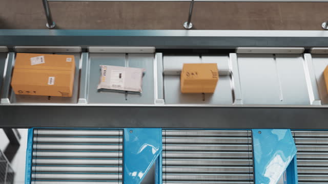Top Down View on a Modern Delivery Station Automated Conveyor Belt System with Retail Parcels, Cardboard Boxes and Online Shopping Orders Being Sorted and Handled Before Shipping to Customers