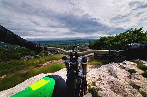 from the first person handlebars of a bicycle on a race through an unpopulated landscape. Close-up of the hands of a male cyclist on the handlebars of a mtb bike outdoors in the mountains