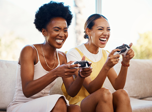 Women on couch playing video games, excited fun and relax in home living room together with internet controller. Online gaming, virtual esports app and happy gamer girl friends on sofa in apartment.