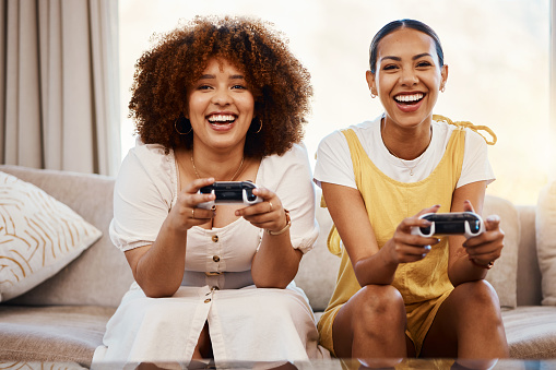 Women on sofa playing video game, excited fun and relax in home living room together on internet with controller. Online gaming, esports and happy gamer friends on couch with virtual app in apartment