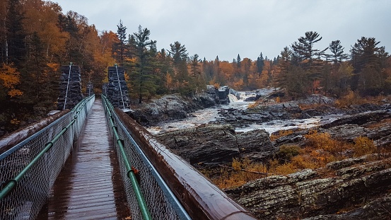 A bridge in the Jay Cooke State Park is surrounded by a tranquil misty forest during autumn