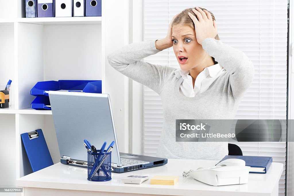 Shocked businesswoman Young businesswoman is shocked by something she sees on her laptop monitor. Frustration Stock Photo