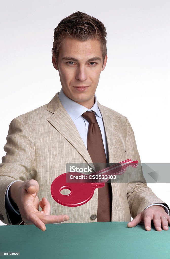 Your key. Young businessman giving a red key Adult Stock Photo
