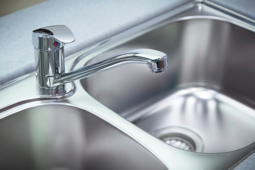 Close up shot for the clean chrome tap and  washbasin in a kitchen