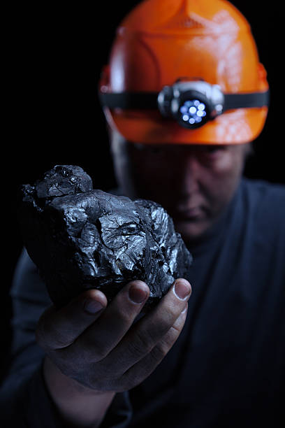 A coal miner holding a piece of coal stock photo