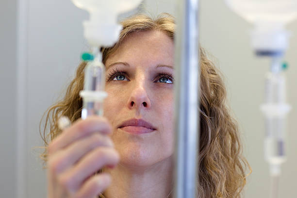 infermiera dai capelli biondi prepara una fleboclisi - infused oil immagine foto e immagini stock