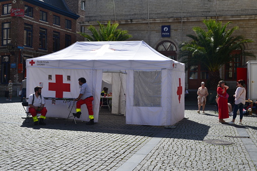 Leuven, Vlaams-Brabant, Belgium - September 4, 2023: once in a year food and non-food market. rescue workers sitting in front of Red cross publicity tent on the old town square