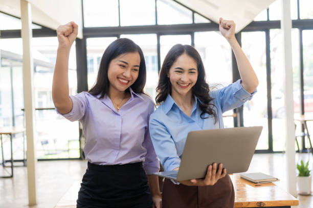 istock Two businesswomen expressed their joy with smiling faces. Raised hands showing joy after successful business, working in the office. 1661306307