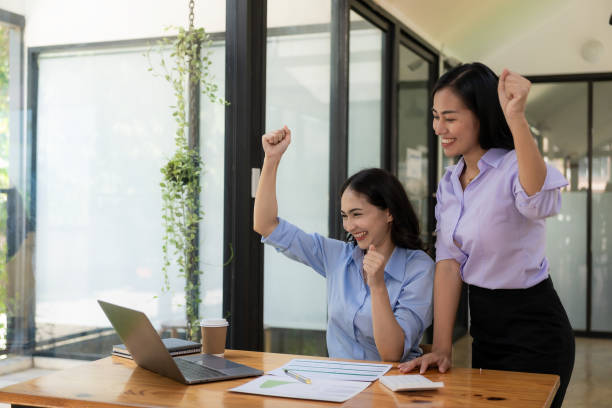 istock Two businesswomen expressed their joy with smiling faces. Raised hands showing joy after successful business, working in the office. 1661306375