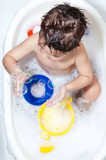 Toddler playing with soap bubbles at bathtime