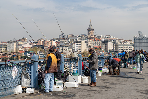 Istanbul, Turkey - April 16, 2023: A picture of Galata Bridge fishermen and the Galata Tower in the distance.